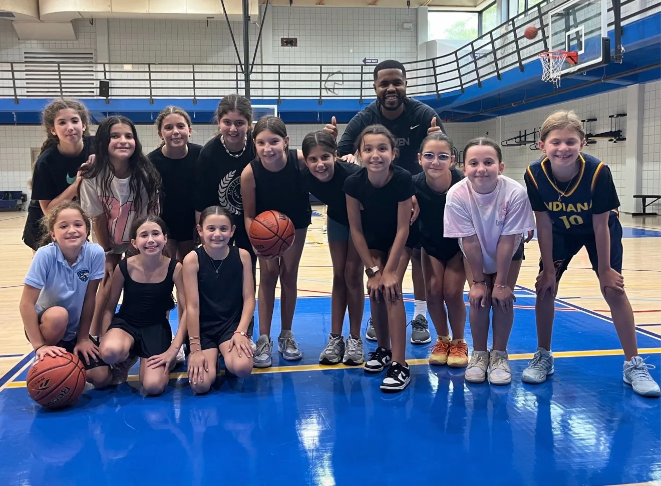 Driven Athletes girls basketball group with their coach on the court