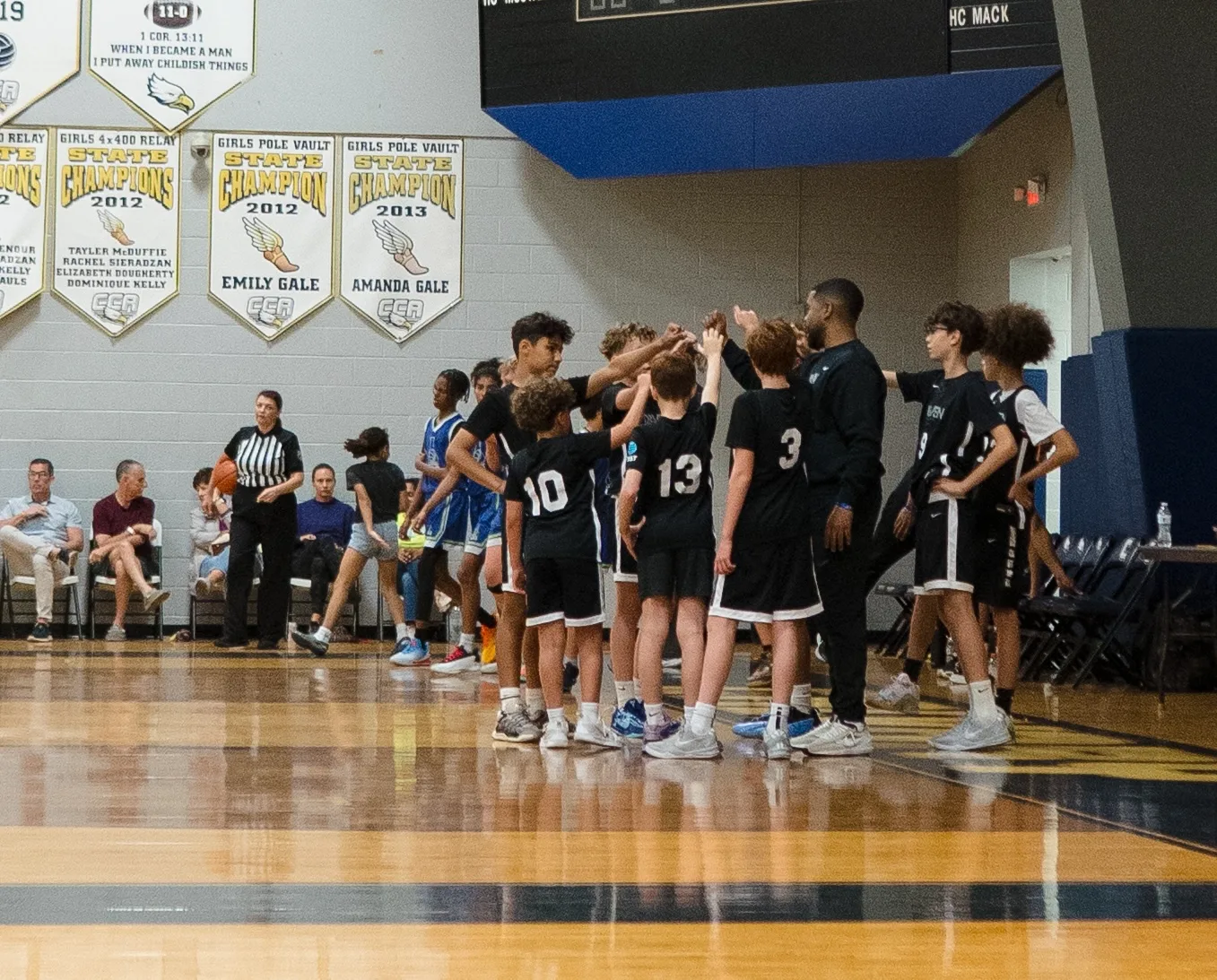 Driven Athletes team huddle with their coach during a game